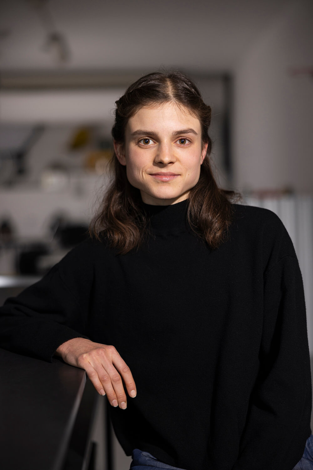 Portraet von Denise, die mit einem leichten Lächeln frontal in die Kamera schaut.