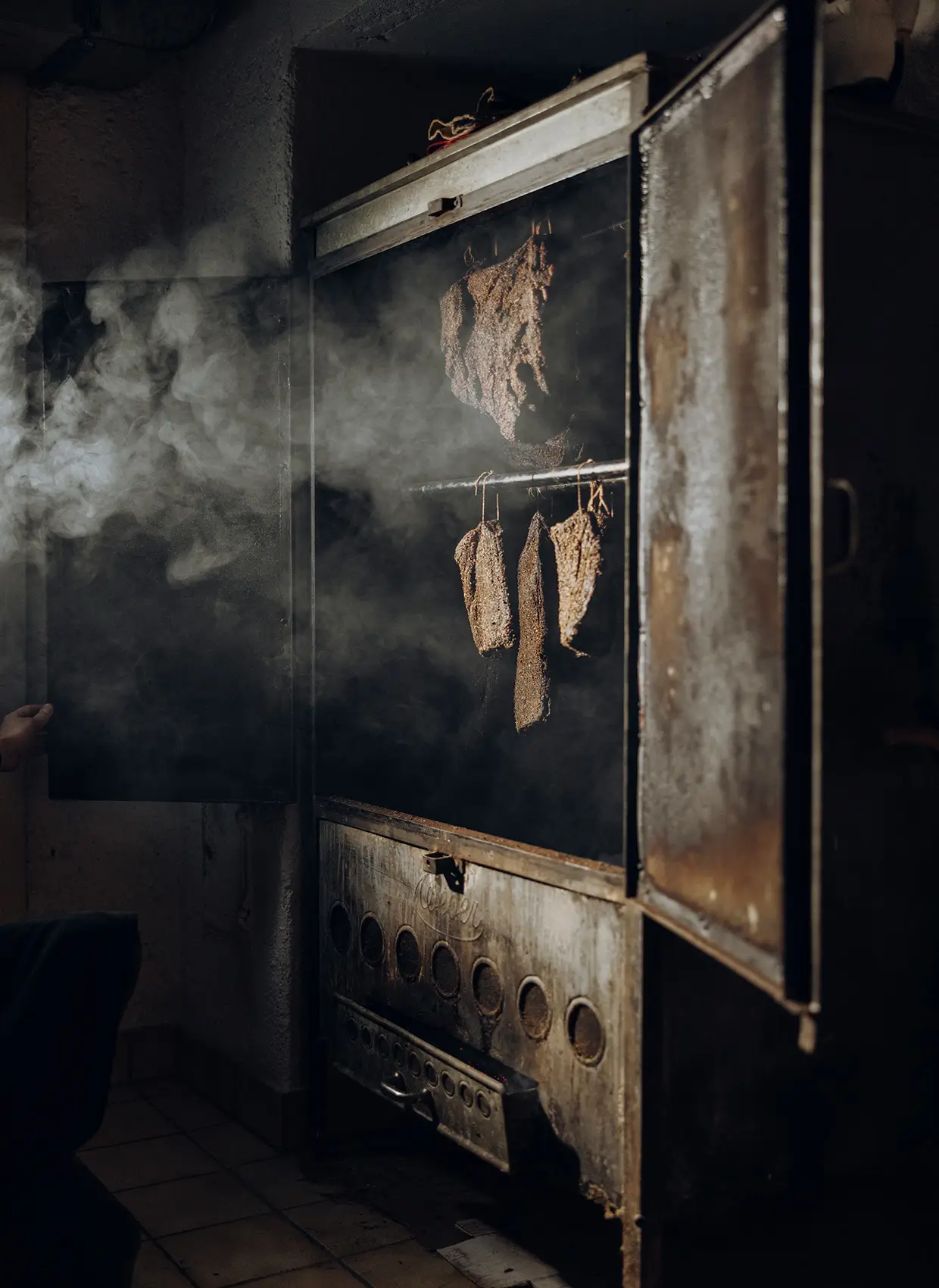 Ein alter geöffneter Räucherofen mit Rauchfleisch.
