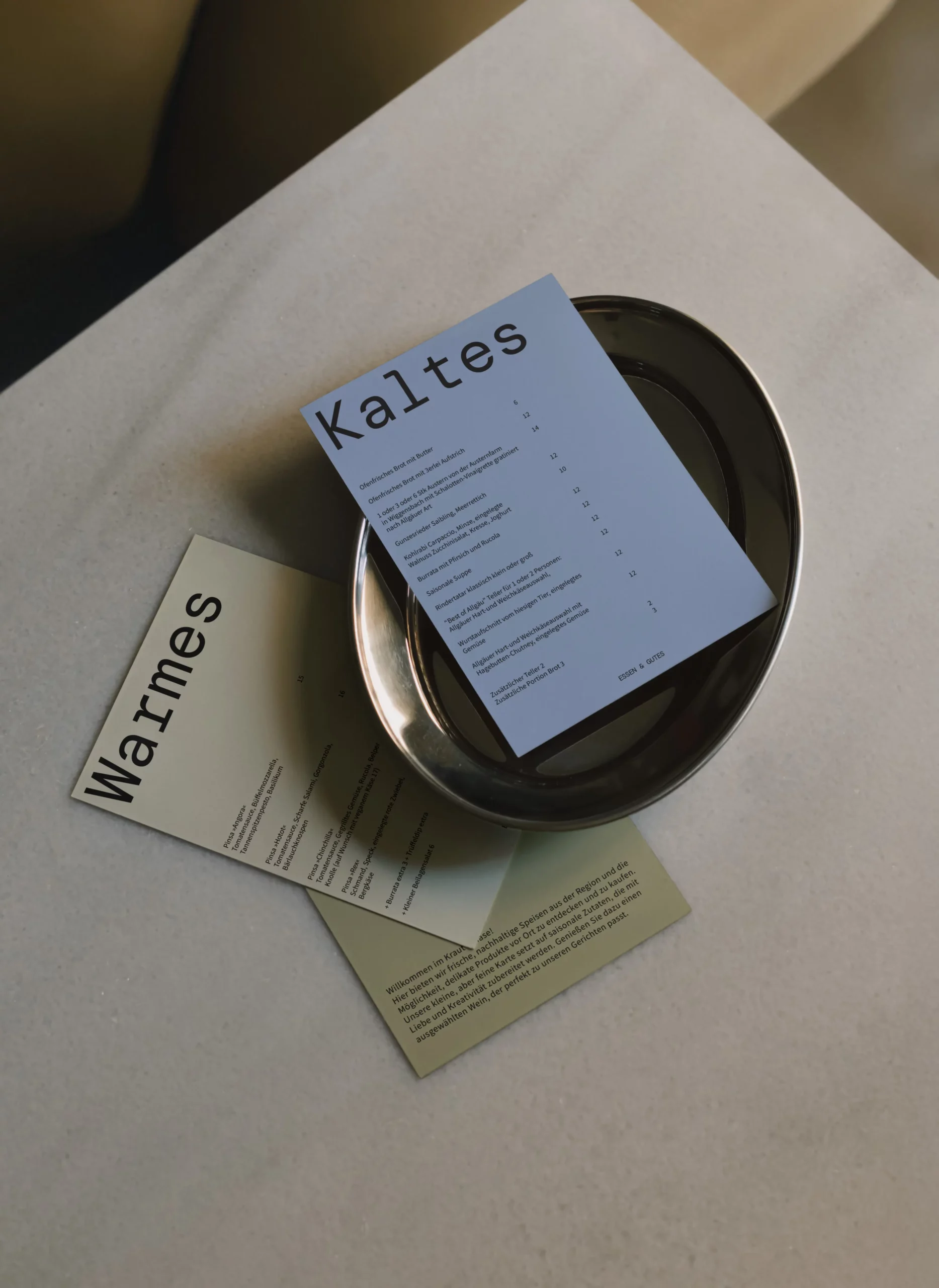 Menükarten in den Farben blau, beige und oliv-grün liegen auf einem Tisch