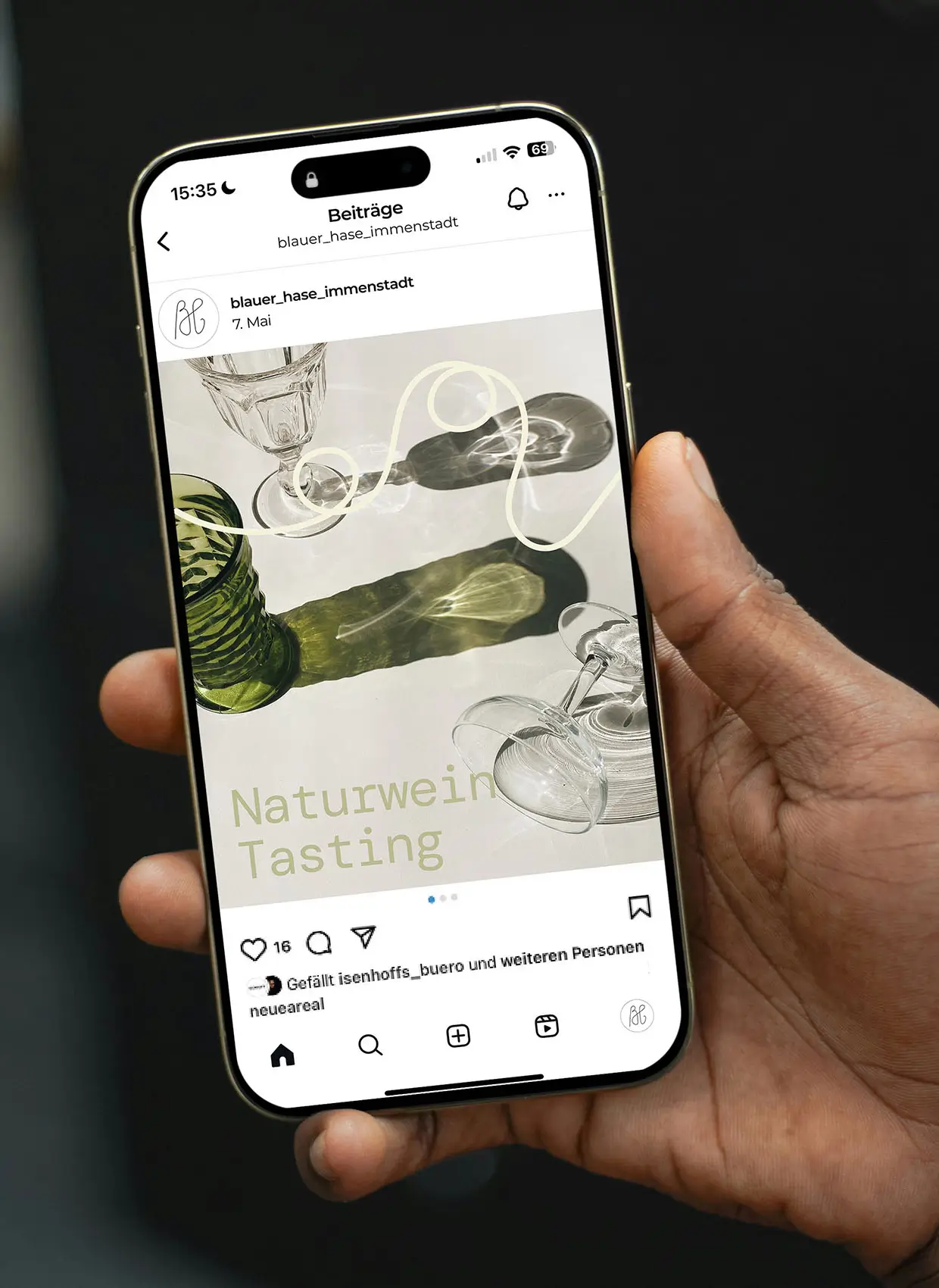 Von Hand gehaltenes Handy mit Instagram Beitrag von Blauer Hase auf Bildschirm