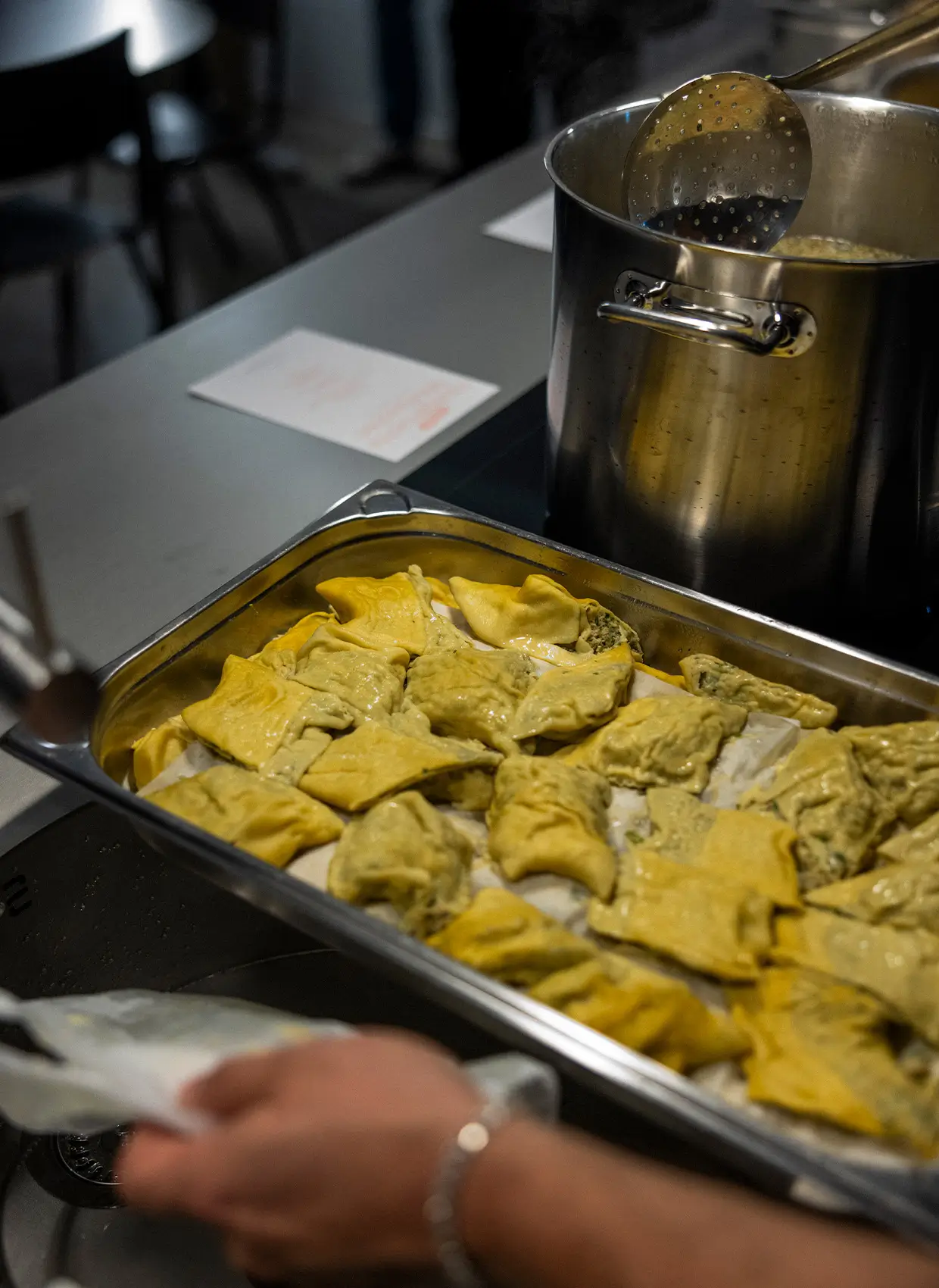 Maultaschen liegen neben einem Topf in einer metallenen Schüssel