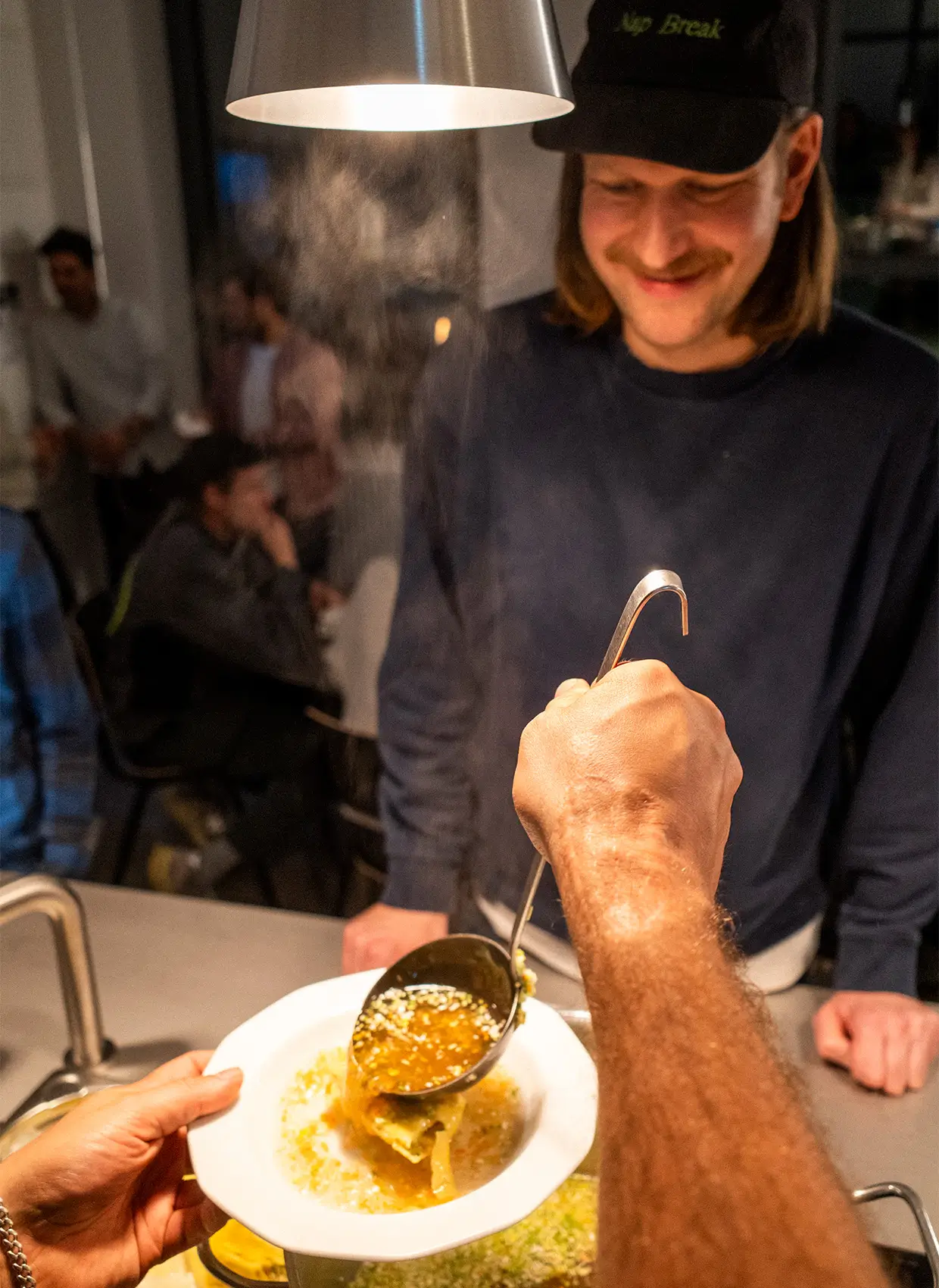 Einem Mann wird Maultaschensuppe auf einem Teller serviert