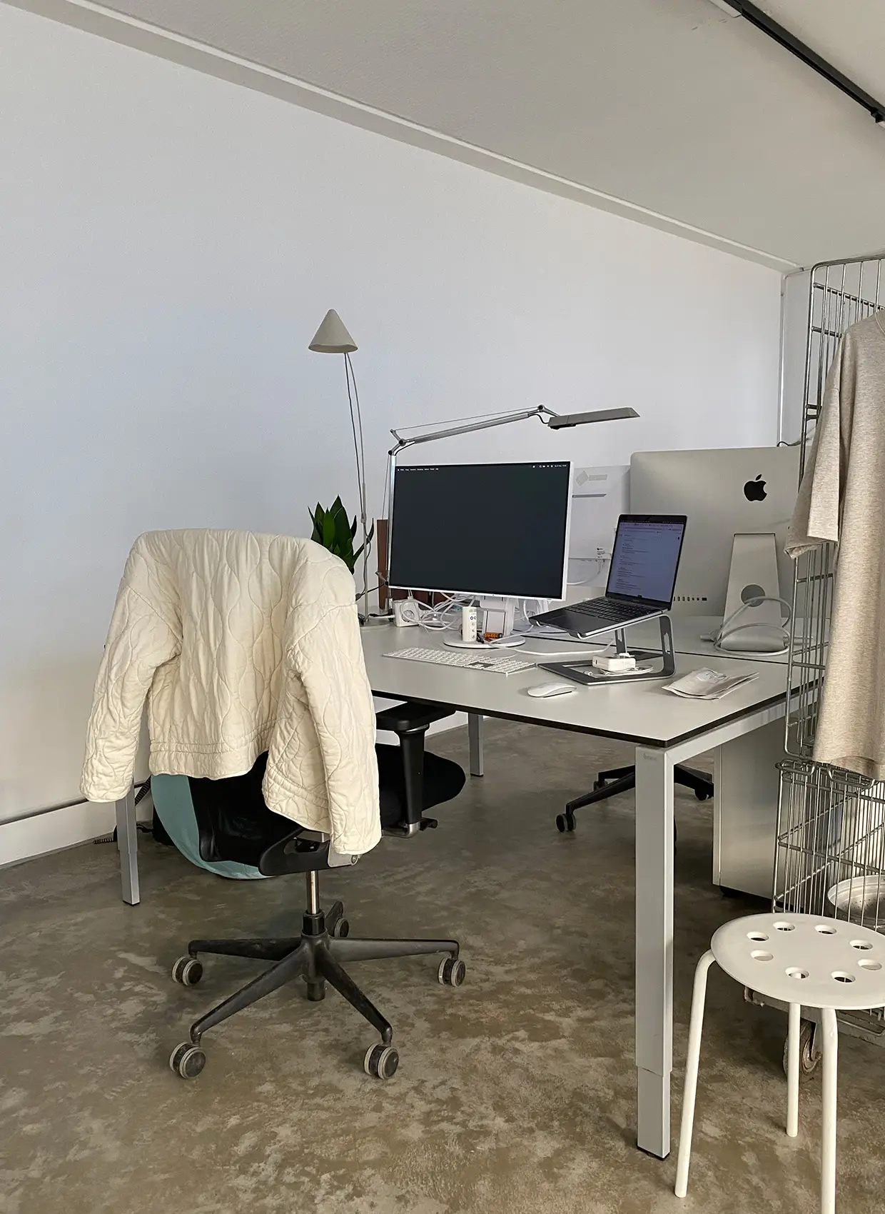 Blick auf Leas Arbeitsplatz (Schreibtisch mit Laptop und Bildschirm, Lampe und Stuhl)